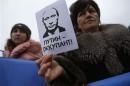 A woman holds a sign with a portrait of Russian President Putin and the words "Putin - Occupant" during a pro-Ukrainian rally in Simferopo