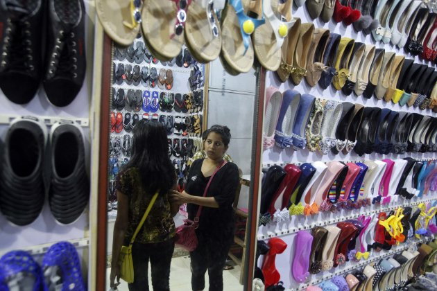 Women are reflected in a mirror as they shop for shoes at a retail store in Mumbai