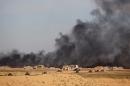 Iraqi government forces vehicles are positioned on the western outskirts of Tikrit, on March 27, 2015, as smoke rises during a military operation to retake the city from Islamic State group jihadists