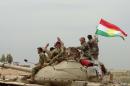 Iraqi Kurdish and Turkmen Shiite forces from the Popular Mobilisation units sit on top of a tank on May 1, 2016 in the northern Iraqi town of al-Bashir after they recaptured the town from the control of the Islamic State (IS) group