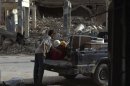 A boy loads a truck with the remains from his shop after it was damaged by what activist say was shelling by forces loyal to Syria's President Bashar Al-Assad Deir al-Zor