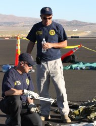In this handout photo from the National Traffic Safety Board taken Sunday, Sept. 18, 2011 at an airfield in Reno, Nev., shows two NTSB officials looking at wreckage from Jimmy Leeward's plane that crash on Friday. Officials say nine people died. (AP Photo/National Traffic Safety Board, HO)