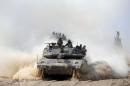 Israeli soldiers ride atop a tank outside the southern Gaza Strip