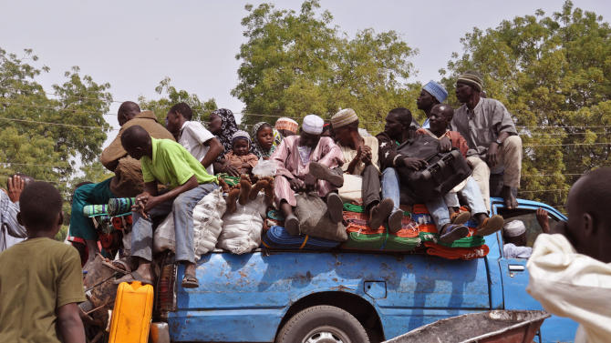 In this photo taken Tuesday, Jan. 27, 2015, villagers sit on the back of a small truck as they and others flee the recent violence near the city of  Maiduguri, Nigeria.  Islamic extremists are rampaging through villages in northeast Nigeria’s Adamawa state, killing, burning and looting with no troops deployed to protect civilians, fleeing villagers said Wednesday. (AP Photo/Jossy Ola)