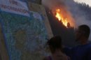 People look at a map of the fire as flames leap at the Beaver Creek wildfire outside Hailey