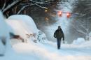 A pedestrian walks along a snow-covered street, Friday, Feb. 14, 2014, in Albany, N.Y. Schools are closed across a swath of eastern New York from the mid-Hudson Valley to the Albany area as the region starts to dig out from 12 to 20 inches of snow dumped by the latest winter storm. (AP Photo/Mike Groll)