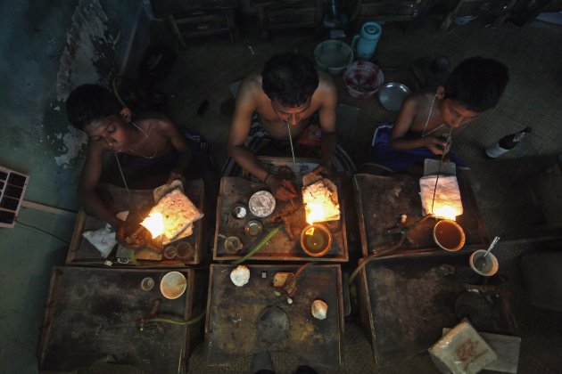 Goldsmiths work on crafting gold ornaments at a workshop in Kolkata