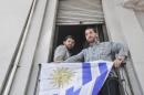 FILE - In this Dec. 11, 2014 file photo, Omar Abdelahdi Faraj, of Syria, left, and Adel bin Muhammad El Ouerghi, of Tunisia, look out at the press from their shared home's balcony decorated with Uruguay's flag in Montevideo, Uruguay. The two former Guantanamo Bay detainees who resettled in Uruguay are planning to tie the knot with women from the South American country. Imam Samir Selim said on Thursday, May 28, 2015 that he would officiate the ceremony. (Ines Guimaraens, Diario El Observador via AP, File) URUGUAY OUT - NOT FOR USE ON URUGUAY WEBSITES OR PUBLICATIONS - NO PUBLICAR EN URUGUAY - NO USAR EN PAGINAS WEBS O EN PAPEL EN URUGUAY