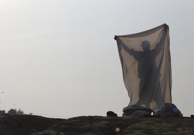 The shadow of a laundryman is reflected on a bed sheet while he washes cloths on the bank of the Narayani River in Chitwan, southwest of Kathmandu