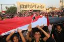 Protesters chant slogans in support of Iraqi Prime Minister Haider al-Abadi as they carry a large national flag during a rally in Tahrir Square in Baghdad, Iraq, Friday, Aug. 28, 2015. Friday's protesters were joined for the first time by followers of Muqtada al-Sadr, a radical, anti-American Shiite cleric. The protesters have staged weekly rallies since last month to press demands for reforms, better services and an end to corruption. (AP Photo/Karim Kadim)
