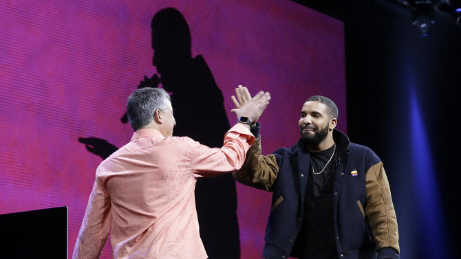 Musician Drake, right, high fives Eddy Cue, Apple senior vice president of Internet Software and Services, during the Apple Worldwide Developers Conference in San Francisco, Monday, June 8, 2015. The maker of iPods and iPhones announced Apple Music, an app that combines Beats 1, a 24-hour, seven-day live radio station, with an on-demand music streaming service. (AP Photo/Jeff Chiu)