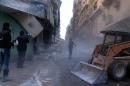A digger arrives to remove the rubble following an airstrike in the northern Syrian city of Aleppo on December 24, 2013