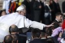 Pope Francis reaches out to touch a child as he arrives to his inauguration Mass in St. Peter's Square at the Vatican, Tuesday, March 19, 2013. (AP Photo/Michael Sohn)