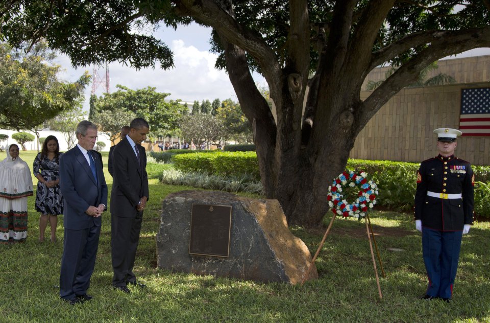 U.S. President Barack Obama and former U.S. President George W. Bush pause for a moment of silence during a wreath laying ceremony to honor the victims of the U.S. Embassy bombing on Tuesday, July 2, 2013, in Dar Es Salaam, Tanzania. The president is traveling in Tanzania on the final leg of his three-country tour in Africa. (AP Photo/Evan Vucci)