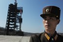 A North Korean soldier stands guard in front of an Unha-3 rocket at Tangachai-ri space center