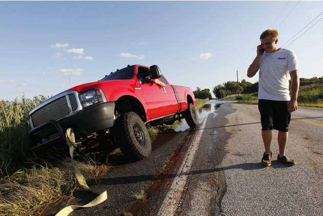John Young makes a phone call as he waits to have his stuck pickup truck pulled out of a ditch on a partially flooded road in Port Penn, Del., Sunday, Aug. 28, 2011, after Hurricane Irene dropped seve