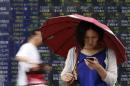 A woman holding an umbrella looks at her cellphone outside a brokerage in Tokyo