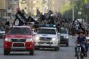 Militant Islamist fighters waving flags, travel in vehicles as they take part in a military parade along streets of Syria's northern Raqqa province
