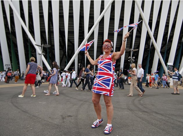 A fan waves Union Jack flags as she arrives for the opening ceremony of the London 2012 Olympic Games at the Olympic Stadium