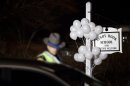 White balloons decorate the sign for the Sandy Hook Elementary School as a Connecticut State Trooper stands guard at the school's entrance, Saturday, Dec. 15, 2012, in Newtown, Conn. A gunman killed his mother at their home and later walked into Sandy Hook Elementary School Friday and opened fire, killing 26 people, including 20 children. (AP Photo/David Goldman)