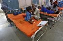 A sick girl Kumari sits next to her grandfather inside a hospital, after she consumed contaminated meals given to children at a school on Tuesday, in Patna