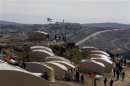 Palestinians, together with Israeli and foreign activists, stand near newly-erected tents in an area known as E1, near Jerusalem