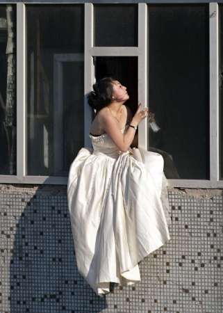 Woman in a wedding gown sits on a windowsill before attempting to kill herself by jumping out of a seven-storey residential building in Changchun