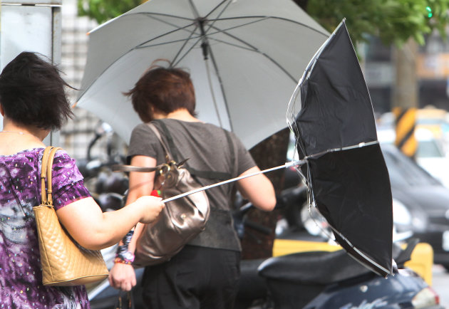 A woman with an umbrella is caught by powerful gusts of wind generated by typhoon Nanmadol in Taipei, Taiwan, Monday, Aug. 29, 2011. Typhoon Nanmadol has slammed into Taiwan, closing schools, workplac