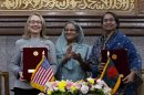 Bangladesh prime minister Sheikh Hasina, center, applauds as U.S. Secretary of State Hillary Rodham Clinton, left, and Bangladesh Foreign Minster Dipu Moni pose for photographs after signing an agreement in Dhaka, Bangladesh, Saturday, May 5, 2012. Clinton is in Bangladesh to press tolerance, democracy and development in one of the world's most impoverished nations that is now in the throes of political turmoil. (AP Photo/Pavel Rahman)