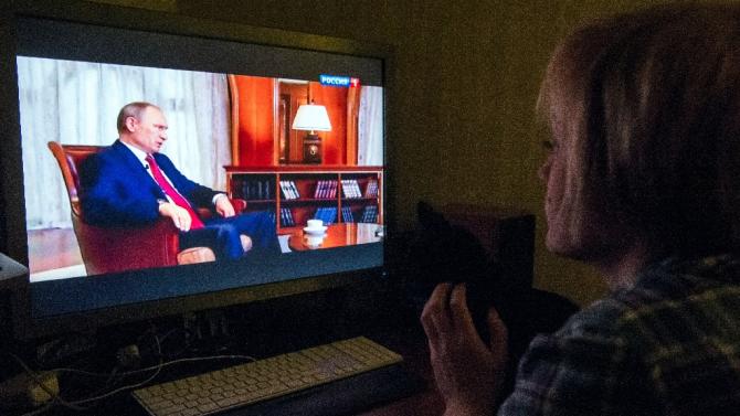 A woman looks at Russian President Vladimir Putin speaking as she watches an internet broadcast of the documentary "Homeward Bound", on March 15, 2015 in Moscow