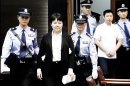 FILE - In this Aug. 9, 2012 file video image taken from CCTV, Gu Kailai, second left, the wife of disgraced politician Bo Xilai, is taken to her trial in the Hefei Intermediate People's Court in Hefei in eastern China's Anhui province. Gu was given a suspended death sentence Monday, Aug. 20, 2012, after confessing to killing a British businessman in a case that rocked the country's top political leadership. A man in white shirt at right is Zhang Xiaojun, family aide of Gu. (AP Photo/CCTV via APTN, File) CHINA OUT, TV OUT