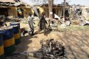 Two residents pass by bombed corner shops attached to Bompai police barracks in Kano in January