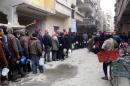 Syrians queue up to receive food from a charity distribution vehicle in the rebel-held Yarmuk Palestinian refugee camp, on the southern outskirts of Damascus, on February 23, 2015