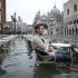 Tourists sit in St. Mark Square during a period of seasonal high water in Venice
