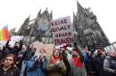 A man holds up a sign reading "No violence against women" as he takes part in a demonstration in front of the cathedral in Cologne, western Germany, on January 9, 2015 where sexual assaults in a crowd of migrants took place on New Year's Eve