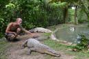 In this Sunday, Sept. 29, 2013 photo, crocodile enthusiast Lawrence Henriques pats the tail of a seven-foot female crocodile at a sanctuary and captive rearing program he founded in the mountain town of Cascade in northern Jamaica. He set up the facility as a domestic market for crocodile meat and even eggs as conservationists worried that the big reptiles, protected by law since 1971 and already endangered by the steady loss of their wetland habitat, might be wiped from the wild altogether. (AP Photo/David McFadden)