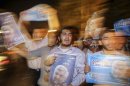 Supporters carry campaign posters for Iranian presidential candidate Jalili on the streets of Tehran