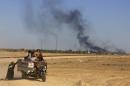 Smoke rises as people flee their homes during clashes between Iraqi security forces and Islamic State group in Hit, 85 miles (140 kilometers) west of Baghdad, Iraq, Monday, April 4, 2016. Families, many with small children and elderly relatives say they walked for hours Monday through desert littered with roadside bombs to escape airstrikes and clashes. (AP Photo/Khalid Mohammed)