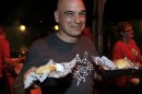 Michael Symon holds his Porky Burgers during the Burger Bash at the Food Network South Beach Wine & Food Festival in Miami Beach, Fka., on Friday, Feb. 24, 2012. (AP photo/Jeffrey M. Boan)