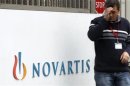 An employee smokes a cigarette beside the logo of Swiss drugmaker Novartis AG in front of a plant in Basel