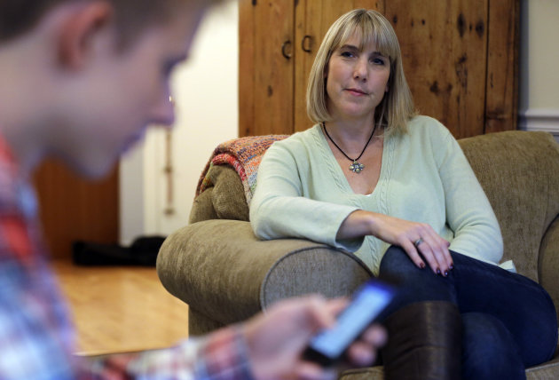 In this Oct. 24, 2013 photo, Amy Risinger, right, watches her son Mark Risinger, 16, at their home in Glenview, Ill. Mark Risinger is allowed to use his smartphone and laptop in his room, and says he spends about four hours daily on the Internet doing homework, using Facebook and YouTube and watching movies. An influential pediatricians group is recommending strict limits on texting, tweeting and other media use, including banning smart phones, iPods and other Internet access from kids' bedrooms. Mark’s mom said she agrees with restricting kids’ time on social media but that deciding on other media limits should be up to parents. (AP Photo/Nam Y. Huh)