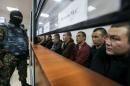 Islamic State supporters, who attacked a National Guard facility in June, sit inside a glass-walled cage during a verdict hearing at a court in Aktobe