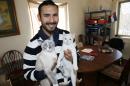 In this Wednesday, Feb. 18, 2015 photo, Alejandro Fuentes Mena holds his two cats at his home in northeast Denver. Fuentes, who settled in the United States illegally as a child, is a Denver elementary school teacher under a pilot program that recruits young immigrants like him to teach disadvantaged students. (AP Photo/David Zalubowski)