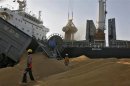 A dumper unloads wheat as a crane loads onto a cargo ship at the Mundra port in Gujarat