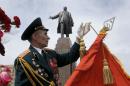 A former Soviet Union army veteran prepares a Soviet army flag as a symbol of victory, in front of the monument of Soviet revolutionary leader Vladimir Lenin, during a Victory Day celebration, which commemorates the 1945 defeat of Nazi Germany, in Kharkiv, Ukraine, Friday, May 9, 2014. Putin's surprise call on Wednesday for delaying the referendum in eastern Ukraine appeared to reflect Russia's desire to distance itself from the separatists as it bargains with the West over a settlement to the Ukrainian crisis. But insurgents in the Russian-speaking east defied Putin's call and said they would go ahead with the referendum. (AP Photo/Efrem Lukatsky)