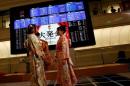 Women, dressed in ceremonial kimonos, stand in front of an electronic board showing stock prices after the New Year opening ceremony at the Tokyo Stock Exchange (TSE), held to wish for the success of Japan's stock market, in Tokyo