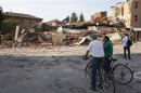 People stand in front of a damaged building in Cavezzo near Modena