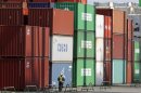 A man rides a bicycle past containers at a port in Tokyo