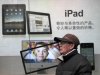 FILE - In this file photo taken on Jan. 26, 2011, a man stands near Apple's iPad advertisement in Shanghai, China.  The official said Monday, Feb. 13, 2012,  that investigators in Shijiazhuang, southwest of Beijing, started seizing iPads last week at the request of a company that filed a complaint with the government accusing Apple Inc. of violating its rights to the iPad name.  (AP Photo/Eugene Hoshiko, File)