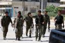Kurdish fighters from the People's Protection Units (YPG) walk along a street in the southeast of Qamishli city